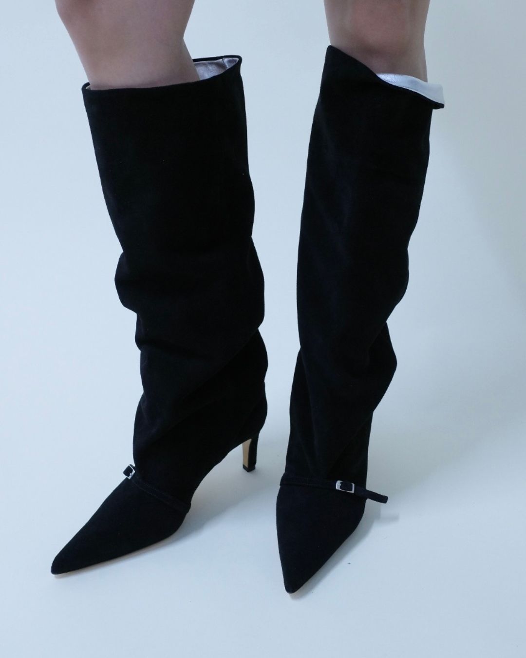 Black knee-high boots with pointed toes on a white background