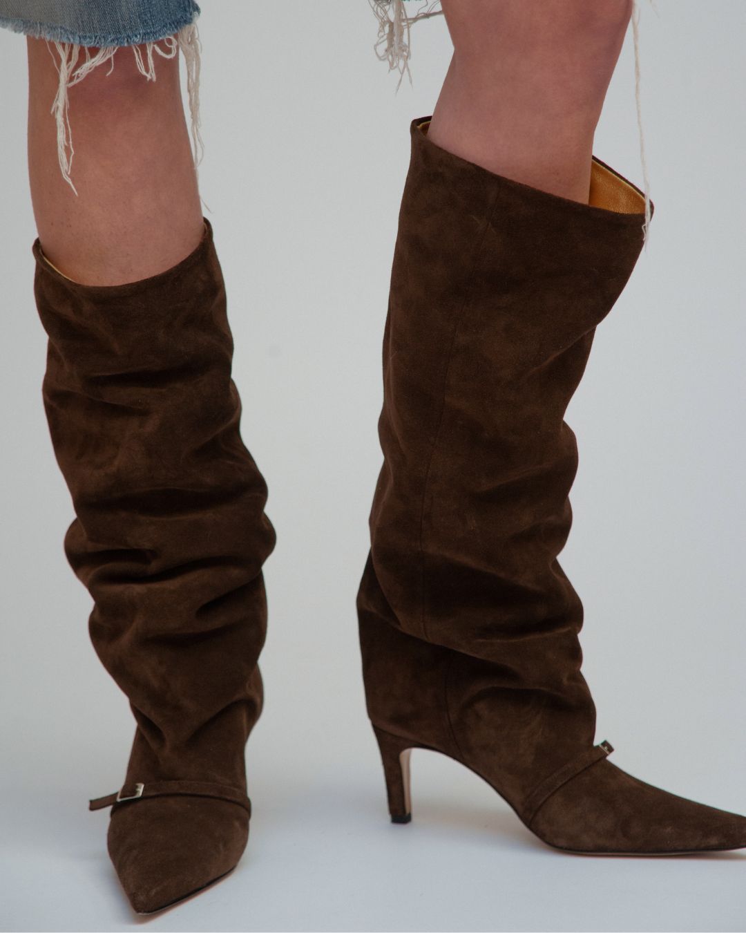 A pair of brown suede boots with a gold leather lining.