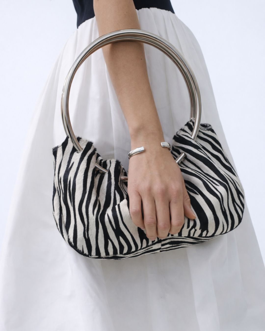 Person holding a KALDA zebra-striped handbag with a white background