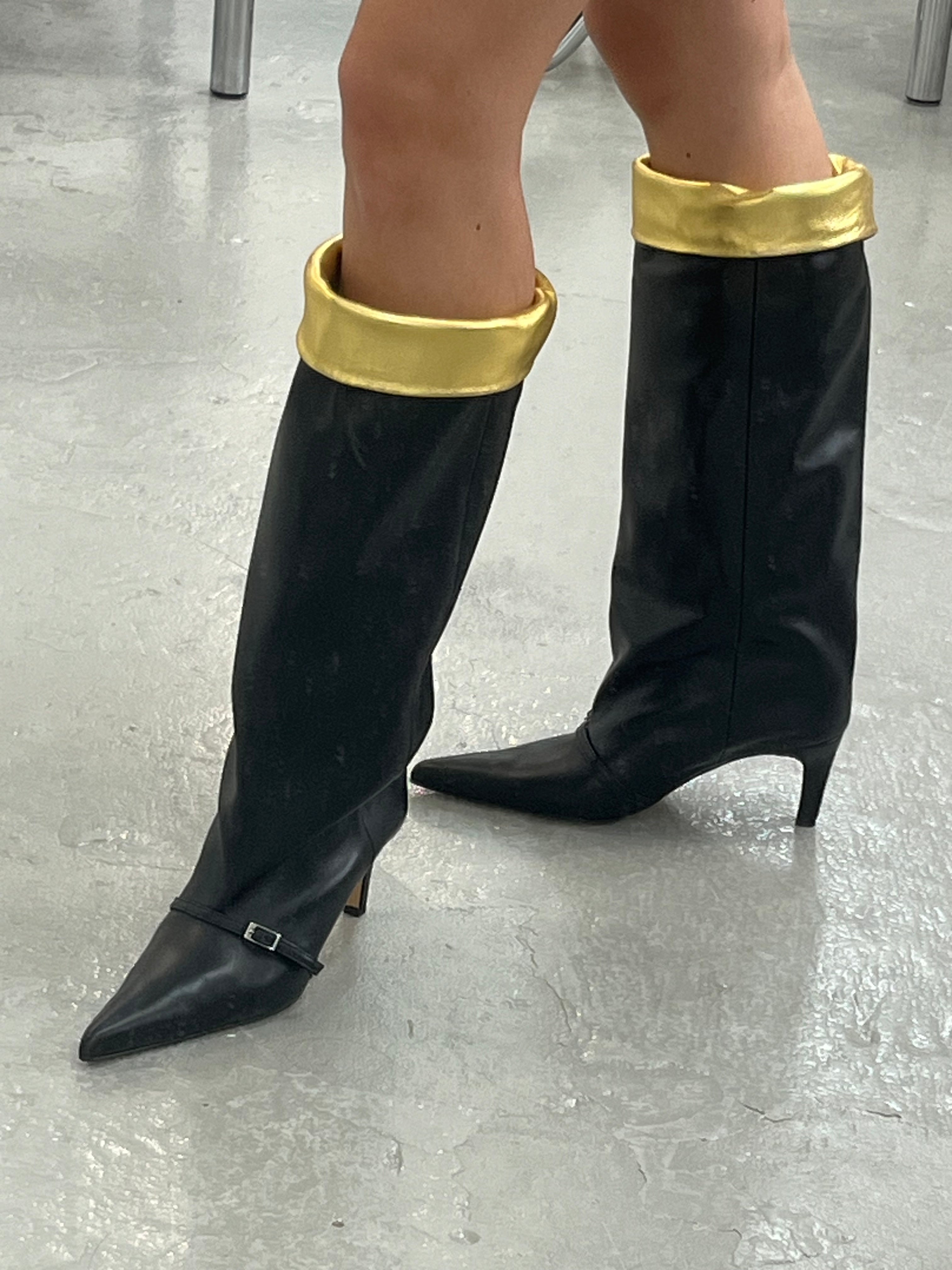 KALDA Black leather knee-high boots worn with gold cuffs