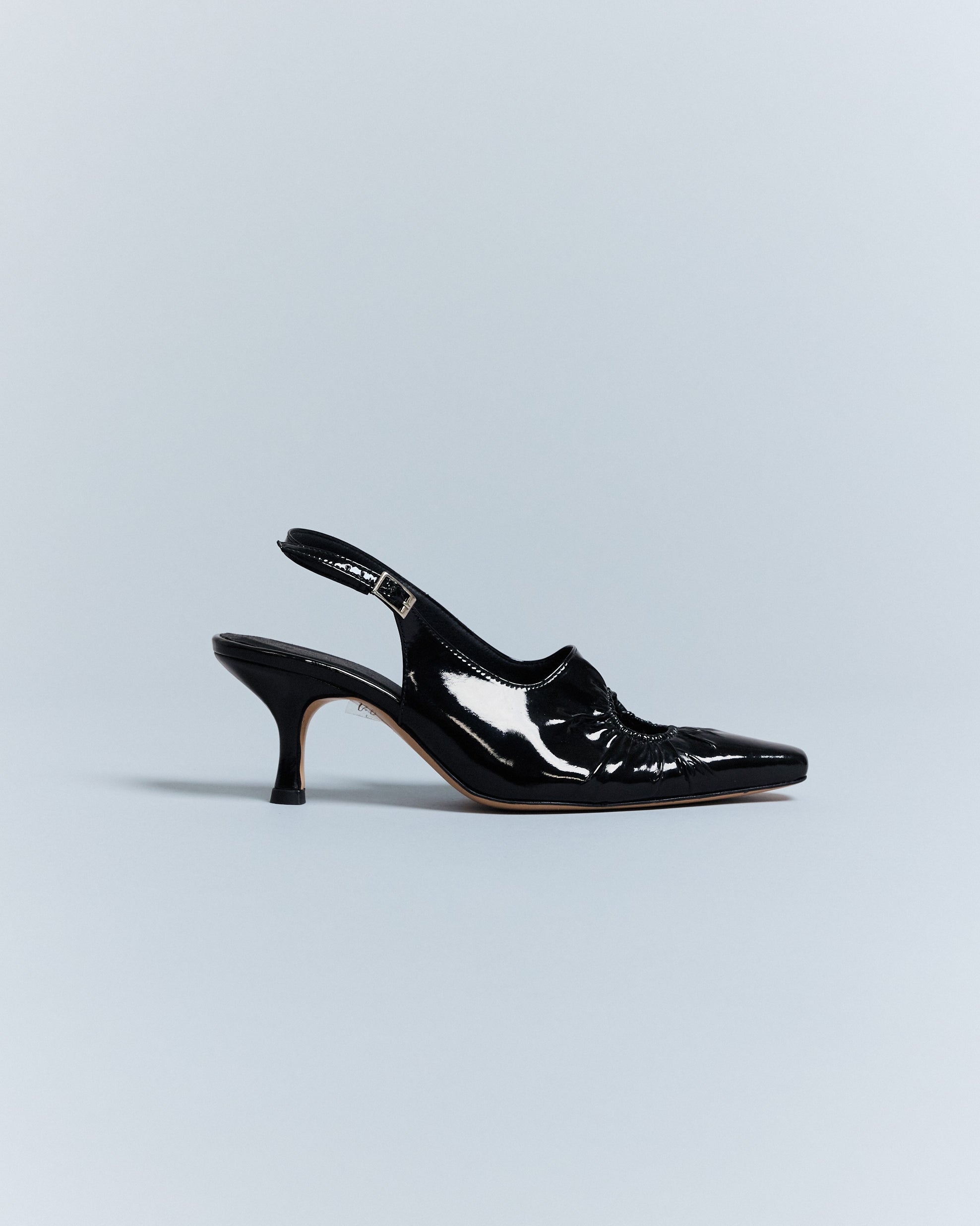 KALDA black patent leather sling-back heel with a signature circle cut-out.