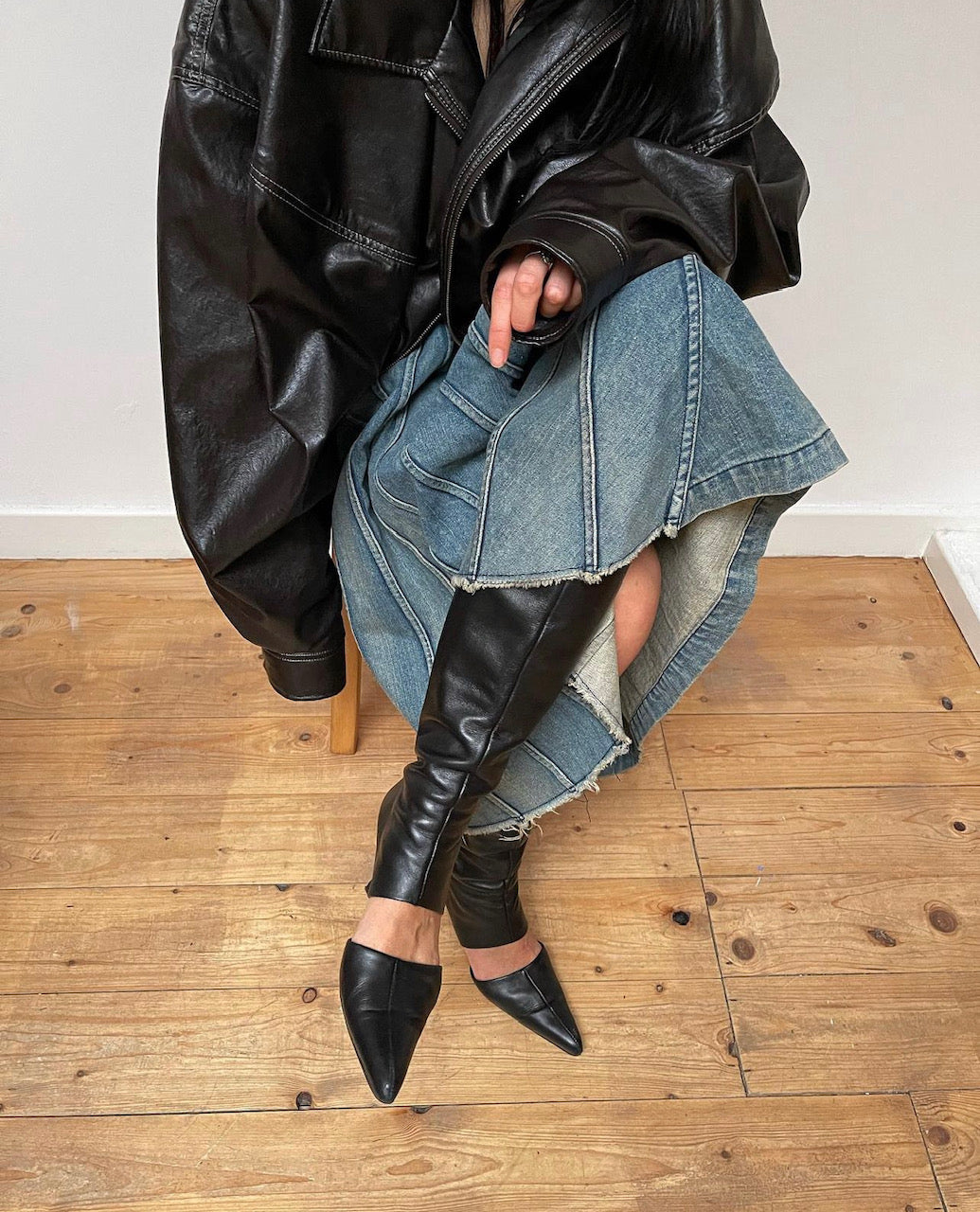 A person wearing black KALDA knee-high leather boots with a cut-out design.