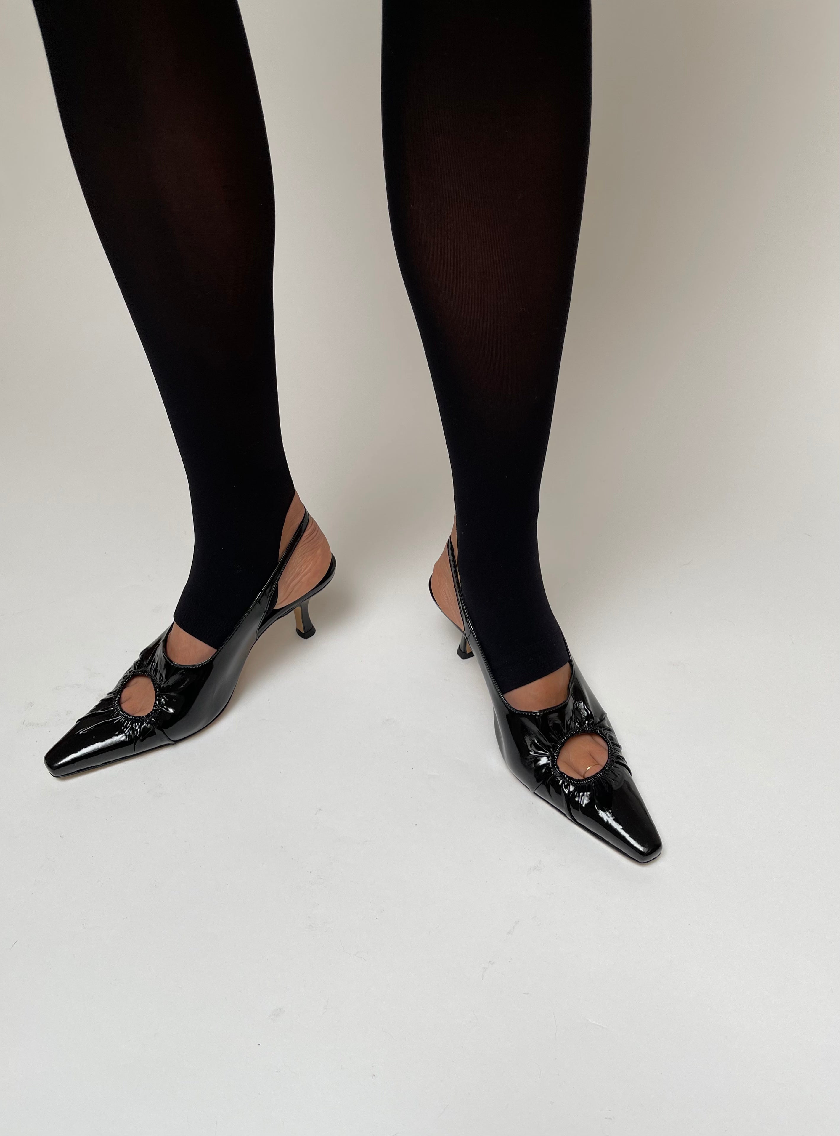 KALDA black patent leather sling-backs with a signature circle cut-out. on a foot