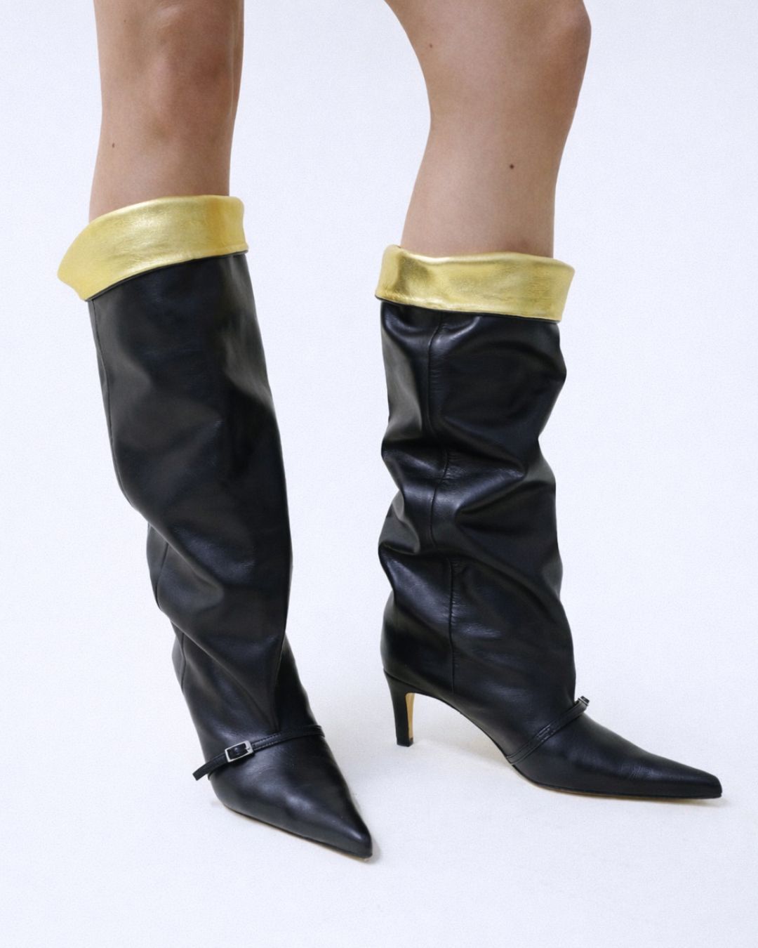 KALDA black knee-high boots with gold cuffs worn by a person on a white background