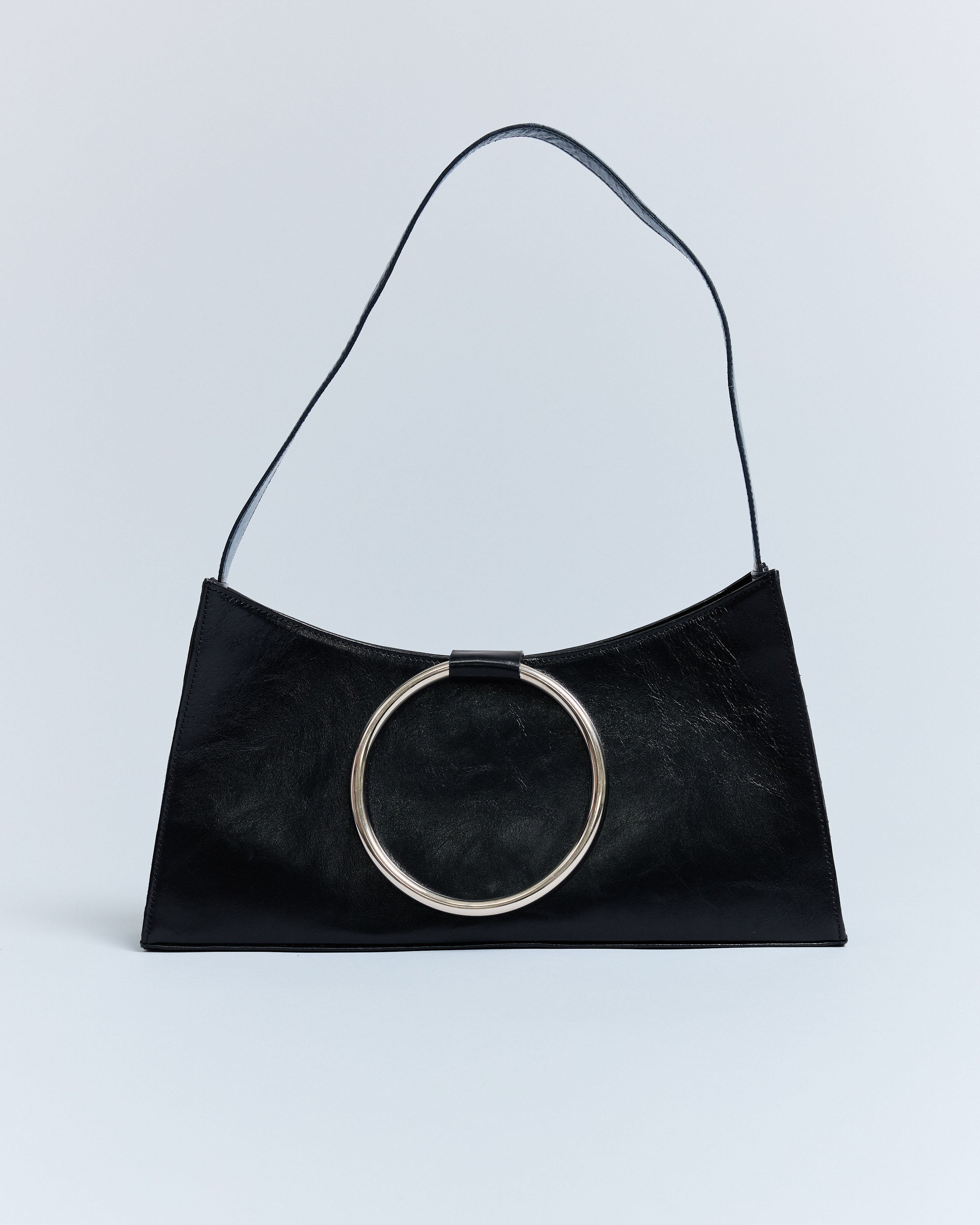 KALDA black leather shoulder bag with a signature metal circle closure and a cotton lining, photographed against a neutral background.