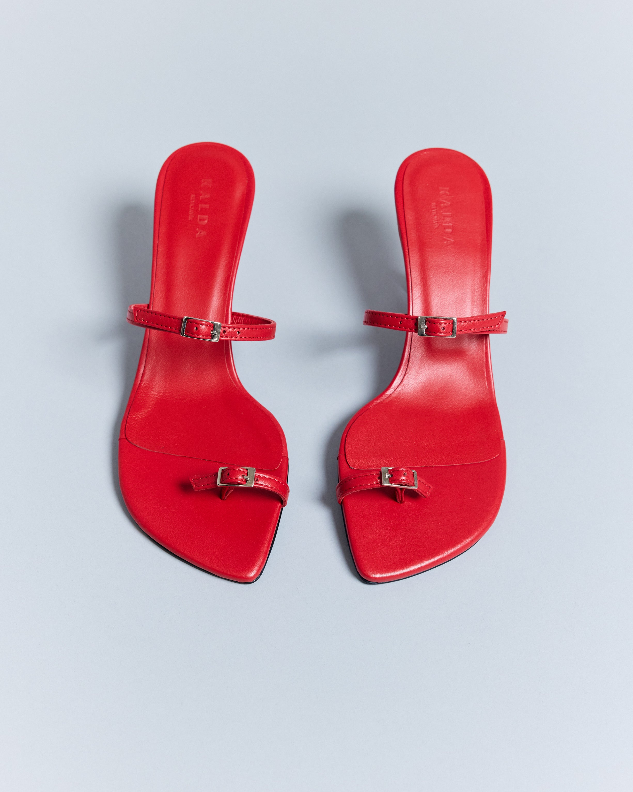A pair of KALDA red summer sandals with a functioning toe belt and a metal heel