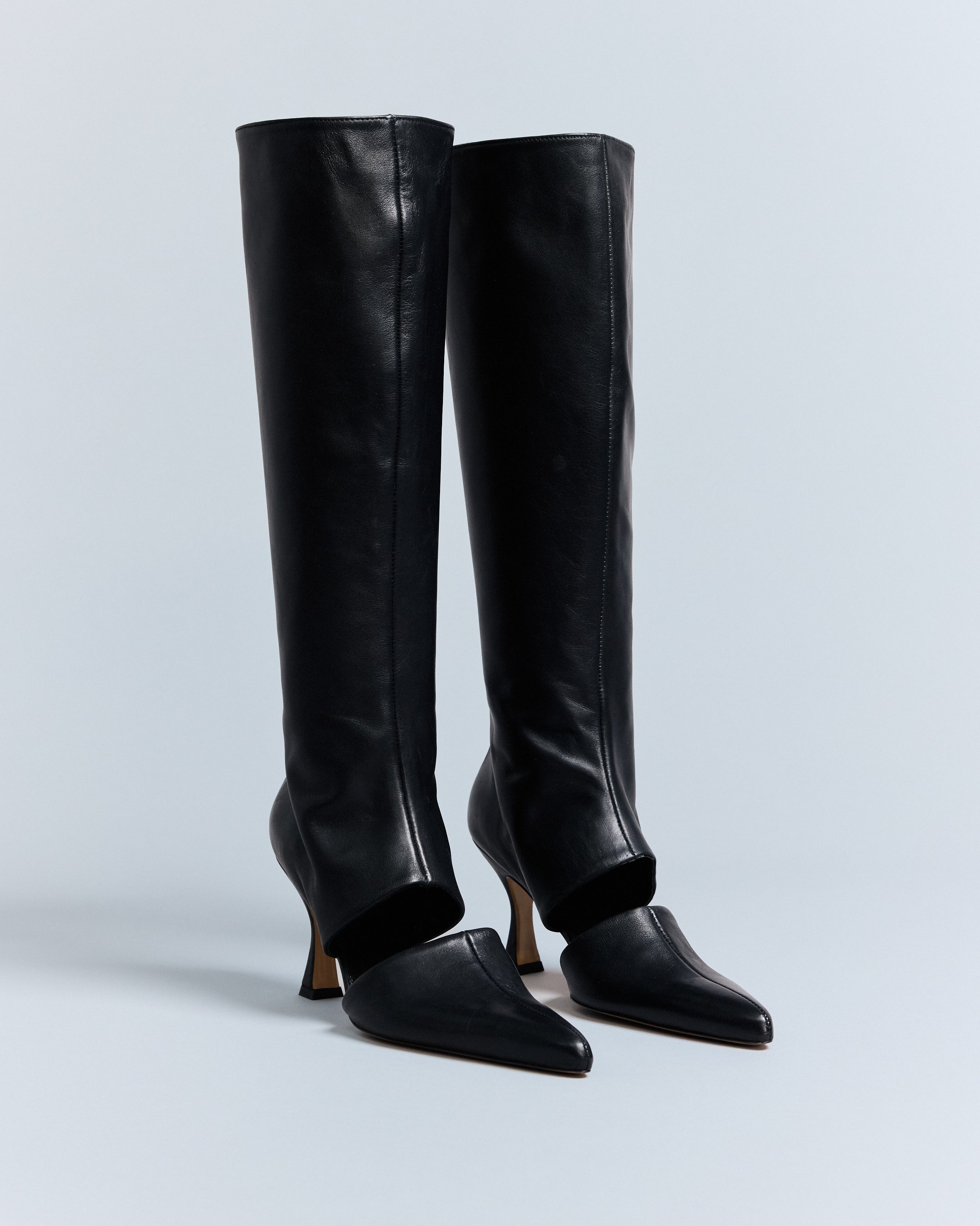 A pair of KALDA black leather knee-high boots with a cut out detail.